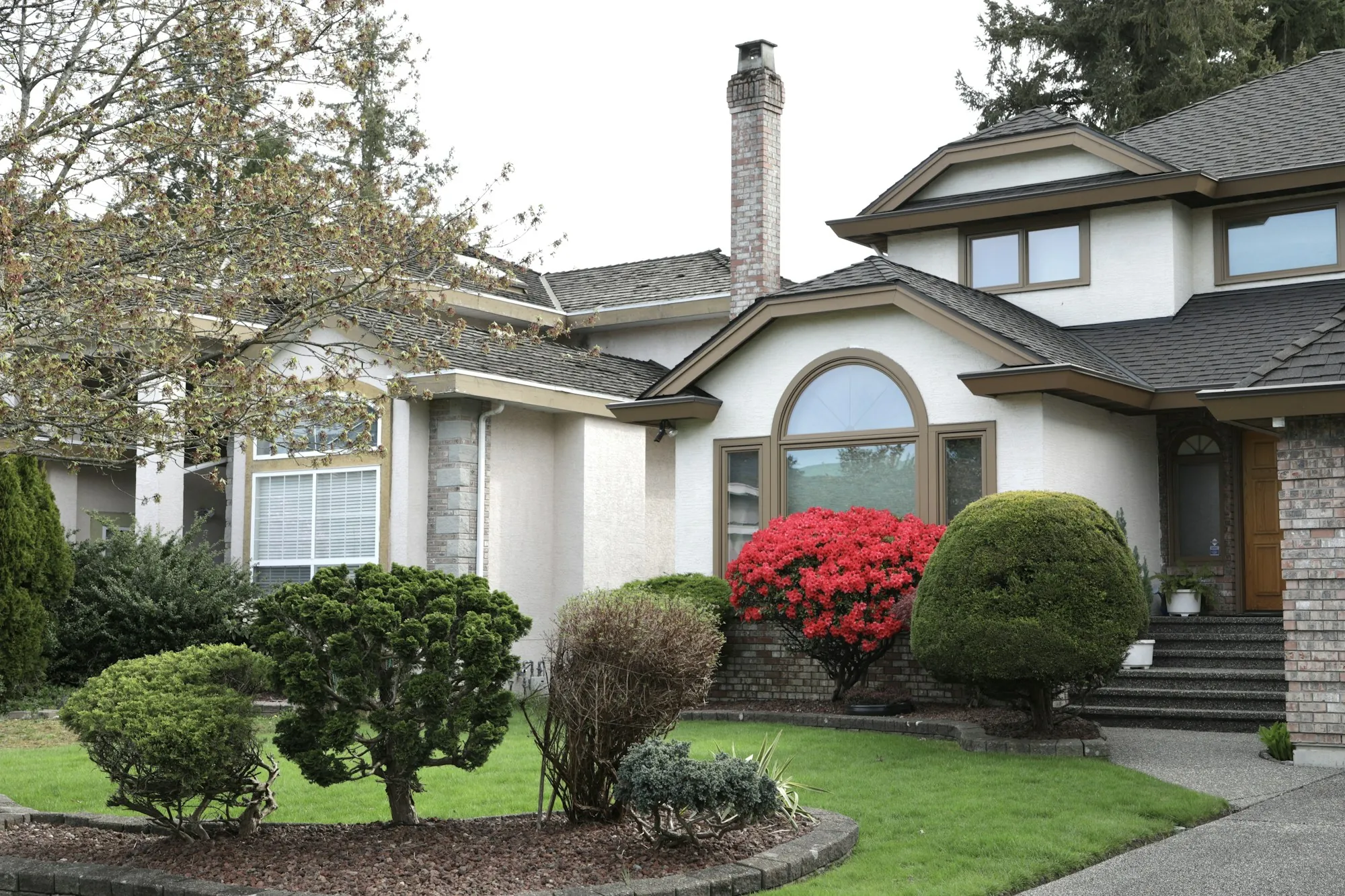 Two-story home with a concrete front walk and shrubs
