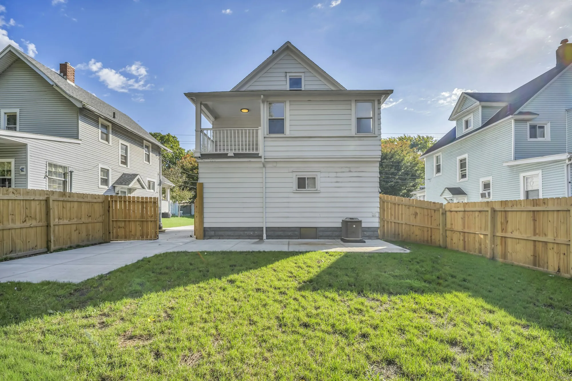 Back of a two-story house with a concrete driveway and fence